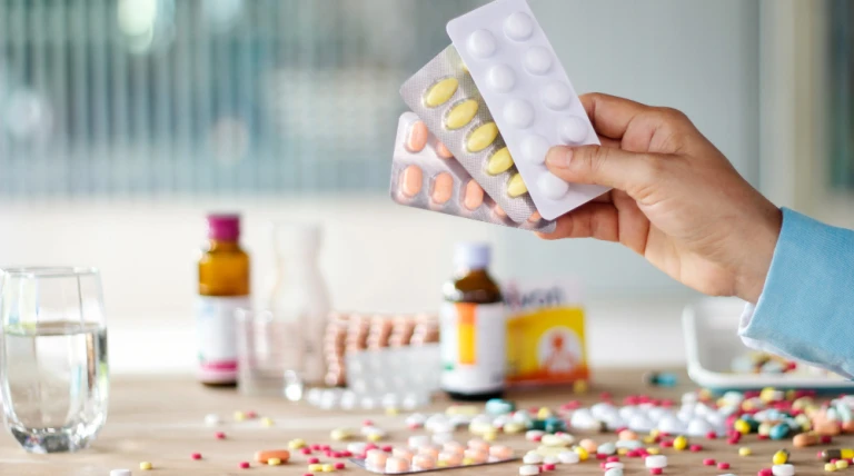 hand-holding-medicines-pill-pack-with-colorful-drugs-spread.webp